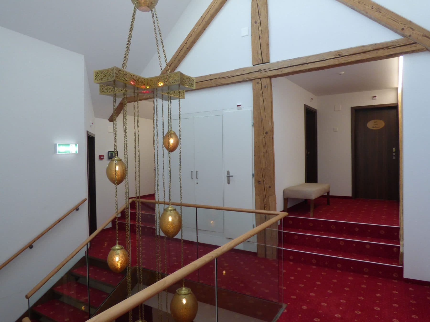Le haut des escaliers rénovés — poutres d'origine et suspensions de laiton