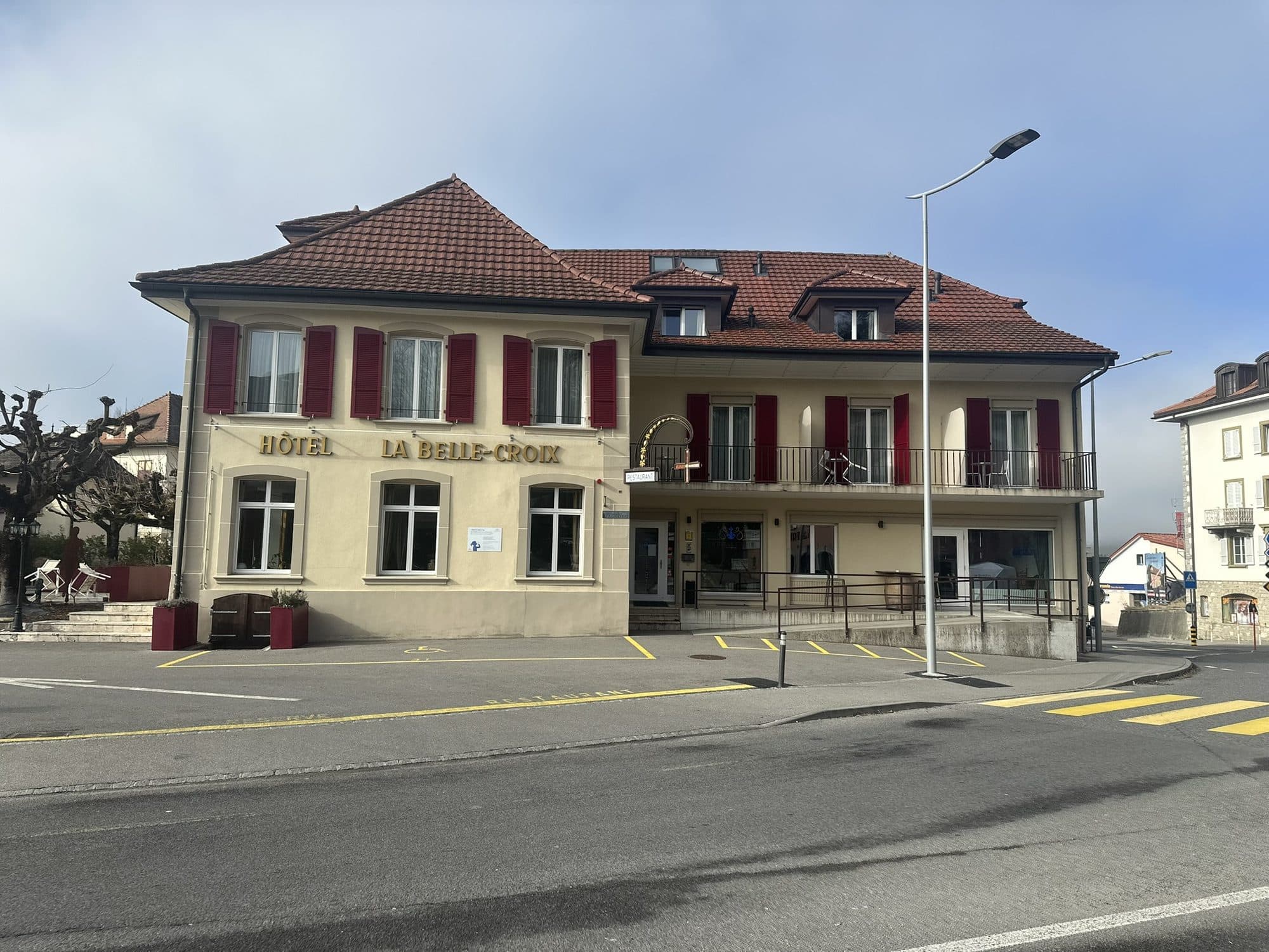La façade de l'Hôtel La Belle Croix à Romont — volets rouges et lettres de laiton
